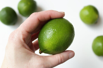 Tropical green tahiti lime being held by caucasian female hand. Citrus fruits, brazilian natural ingredient for vegetarian, vegan healthy and organic diet meal.