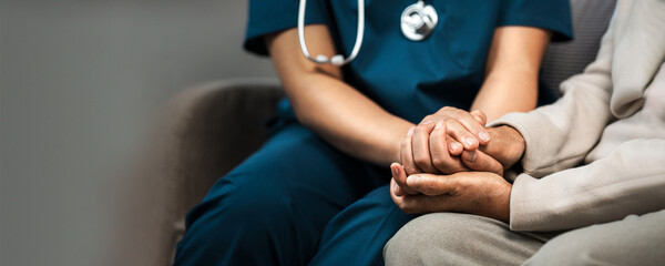 A female nurse caregiver holds hands to encourage and comfort an elderly woman. For care and trust...