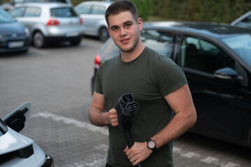 Man Holding EV Charging Cable in Parking Lot