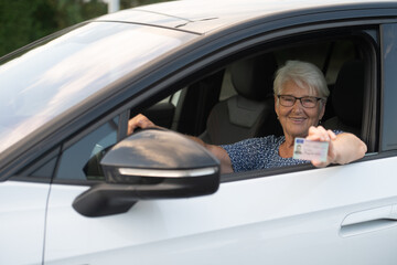 Senior Woman Proudly Displaying Driver’s License from Car