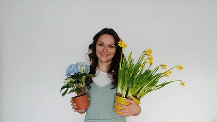 Beautiful young woman florist with flowers on white background smiling at camera