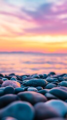 Obraz premium Colorful sunset over a tranquil beach with smooth pebbles lining the shore reflecting vibrant hues of purple and orange