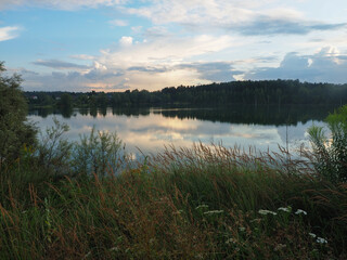 Beautiful summer landscape with lake and forest in the background at sunset
