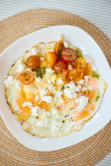 Fried eggs with marinated cherry tomatoes, herbs and feta cheese