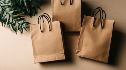 Assortment of brown paper shopping bags with black handles on a neutral background with green leaves