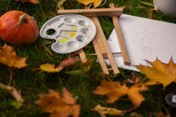 autumn composition of pumpkin, basket and art supplies