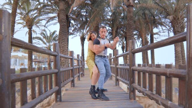 Couple Dancing Latin Dance on a Wooden Bridge with Palm Trees in the Background. Pareja Bailando Baile Latino en un Puente de Madera con Palmeras de Fondo