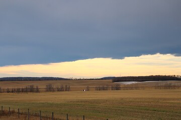 A cloudy prairie landscape scene showing a chinook arch at the horizon. An autumn scene.