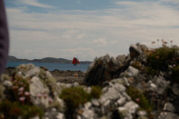 sail boat on loch sea through shore rocks