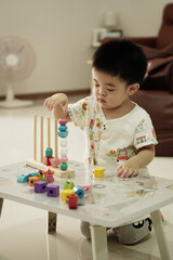 Asian boy playing wooden toy on table at home