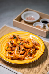 still life, shrimps on a yellow plate, spices and sauce behind them