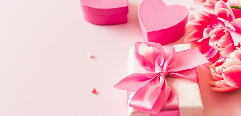 Pink hearts and gift box with ribbon on a light pink background