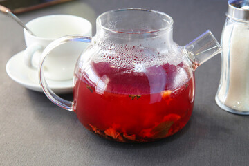 Red hot fruit tea brewed in a glass teapot