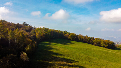 Vista aerea dei coloratissimi boschi e prati dell'Appennino modenese durante una soleggiata giornata d'autunno