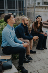 Business people engage in a casual outdoor meeting in an urban city area. The setting fosters an informal and creative atmosphere, encouraging open communication and collaboration among the team.