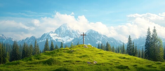 A cross on top of a grassy hill with mountains in the background