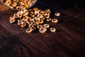Round cornflakes spilled from a glass jar on a wooden surface
