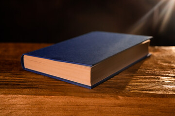 closed book on a wooden bench with a dark background