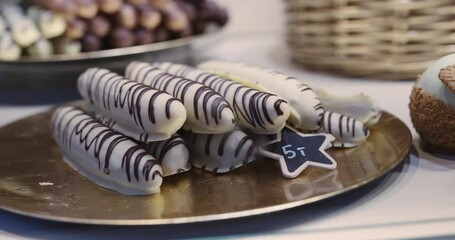 Artisan chocolate candies displayed on a golden plate at a festive Christmas market in Cologne, Germany.