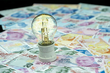 Increase in Electricity Prices. Macro detail shot of burning light bulb on representative Turkish lira.