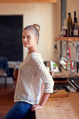 Portrait, smile and woman in kitchen, relax and chilling in weekend, table and peace in morning and house. Break, wellness and person in apartment, comfortable and rest on counter, girl and Germany