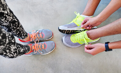 Fitness, shoes and feet of people for running with race, marathon or challenge training. Sports, sneakers and top view of athletes tie laces for cardio workout or exercise preparation in city.