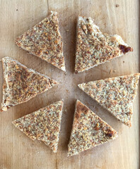 triangular nut-topped pastry on wooden surface
