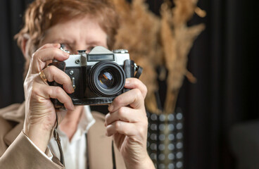 A retro camera in the hands of an adult woman. Photographer. Hobby.