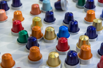 Close-up view of group of various multi coloured empty aluminium packages for coffee capsules (or coffee pods) lying on grey table. Coffee tool background. Copy space. Recyclable material theme.