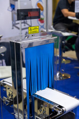 Close-up view of empty white narrow conveyer belt and blue curtain of x-ray inspecting machine in...