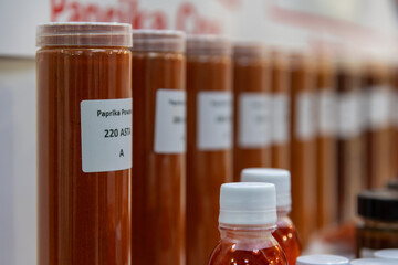 Close-up view of group of flasks with various red paprika seasoning samples (with different quality and color grades). Soft focus. Copy space. Professional food industry theme.
