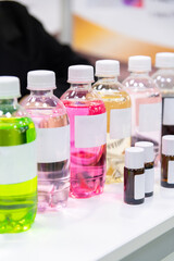 Close-up side view of group of plastic bottles with multi coloured beverages and white blank labels. Soft focus. Copy space. Drinks industry theme.