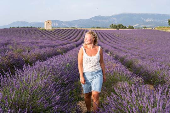 Young blonde woman enjoying a sunrise walk in Valensole lavender fields in Provence, France