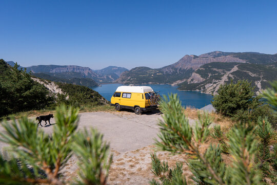 Retro camper van parked on the cliffs with the view of Serre-Poncon lake, Ecrins national park, France