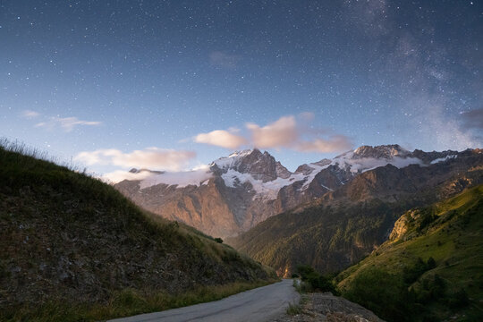 Night starry sky over mountain road in Ecrins national park, France. Long exposure astrophotography