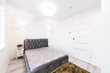 Wide Angle of Home Bedroom Interiom. King Size Double Bed and Wardrobe in Background. White Walls. Family Home. Closed White Wooden Door