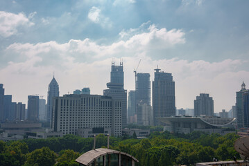 The image captures Shanghai's skyline, featuring Jin Mao Tower and Shanghai World Financial Center amidst modern skyscrapers and lush greenery.