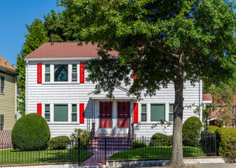 Charming two-story multi-family house with white siding and red shutters in Brighton, Massachusetts, USA