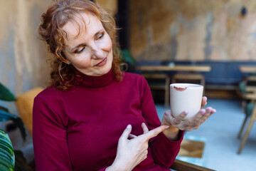 Mature woman enjoying coffee with lipstick imprint on cup
