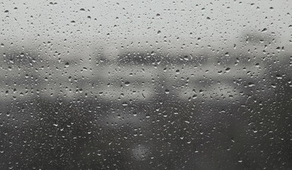 Raindrops on window glass in autumn. Rain outside window.  Rainy weather. Cold rainy autumn day. Background with raindrops on window. Raindrops close up. Bad weather concept.