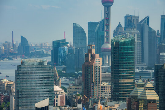 View of Shanghai's skyline featuring the Oriental Pearl Tower, modern skyscrapers, and the Huangpu River, highlighting the city's architectural diversity.