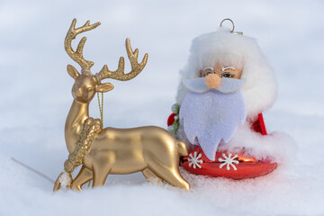 Toy santa claus or ded moroz in christmas clothes riding golden deer on white snow. Xmas and new year holidays decoration. Template for design christmas bauble. Fairy story of festive winter season.