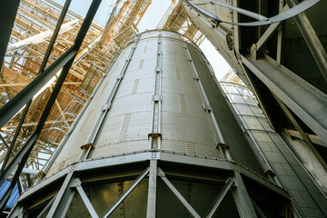 Silo Grain bin with conical bottom. View from bottom to top. Grain dryer complex. Granary with loading tower.