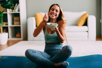 Happy sporty woman eating healthy breakfast at home