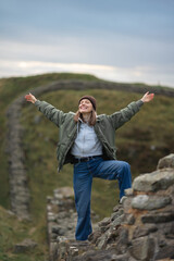 Woman tourist with Hadrian's wall on the background, happy Traveler travel Northumberland, United Kingdom. Destination and Vacation