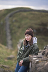 Woman tourist with Hadrian's wall on the background, happy Traveler travel Northumberland, United Kingdom. Destination and Vacation