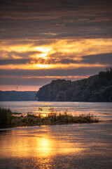 Sunrise idyll landscape on a river with a cloudy sky at golden hour