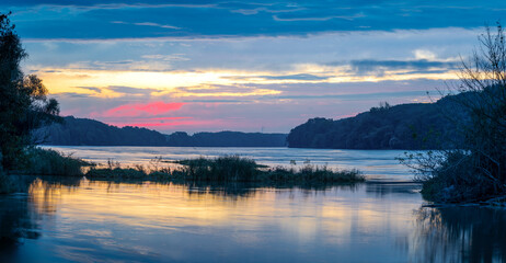 Sunrise idyll landscape on a river with a cloudy sky at blue hour