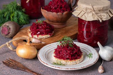 Homemade appetizer of beets, carrots, onions and garlic on toasted bread and in jars