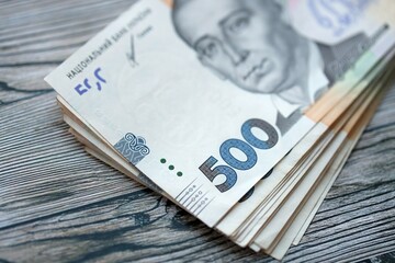 Many five hundred hryvnia money bills lies on wooden background. Ukrainian national currency close...